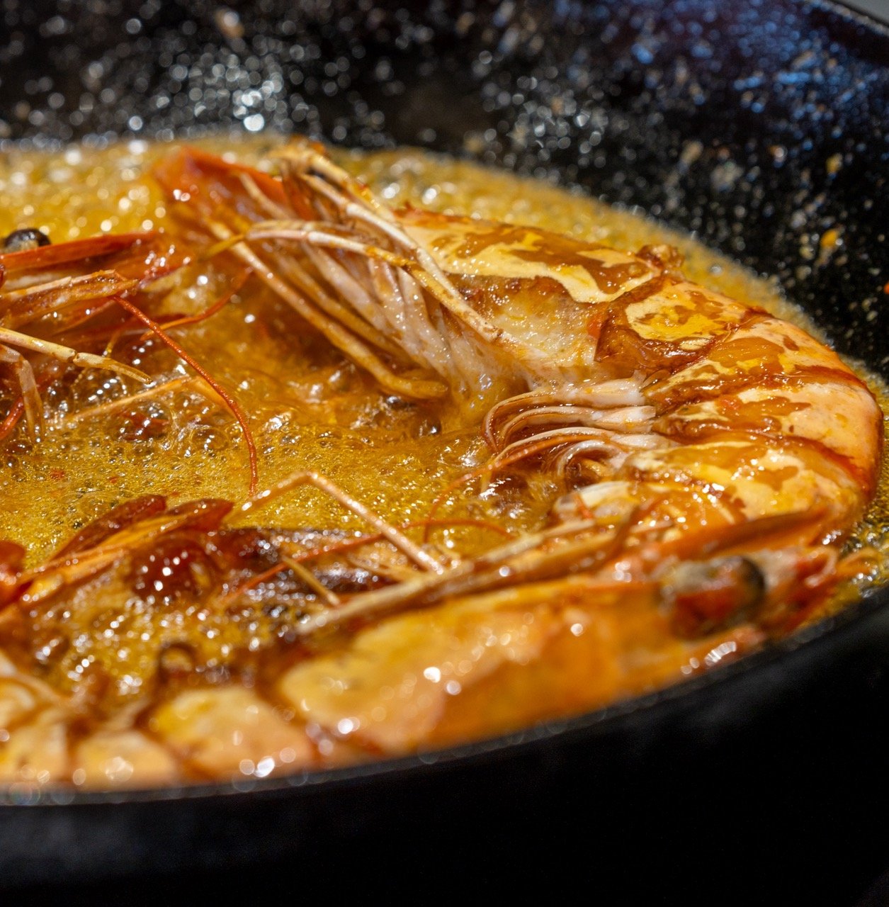 Grote garnalen koken in een pan met hete olie.